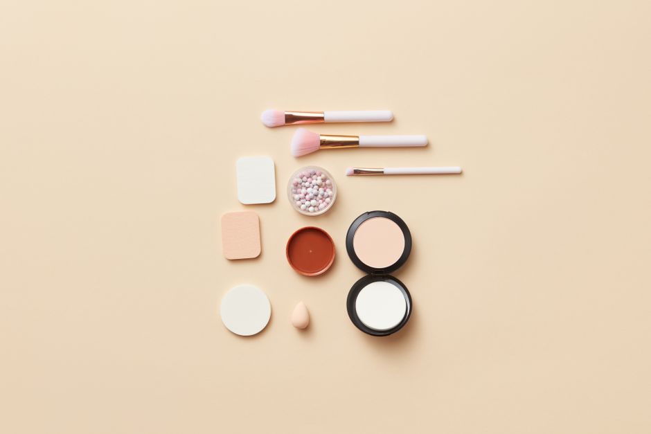 A flat lay of makeup brushes and cosmetics on a beige background, perfect for beauty theme