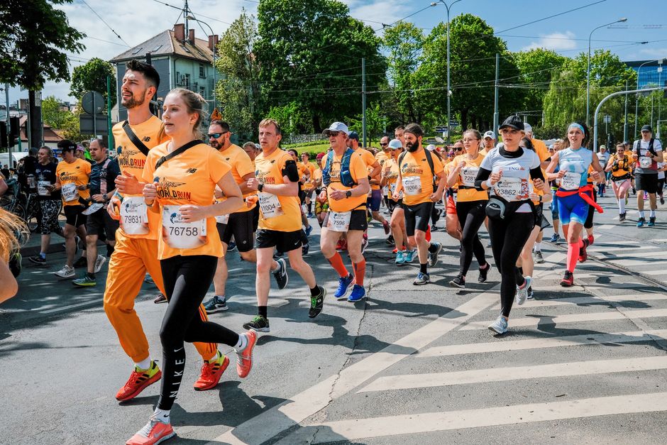 A diverse group of runners competing in a sunny marathon event in Poznań, Poland.