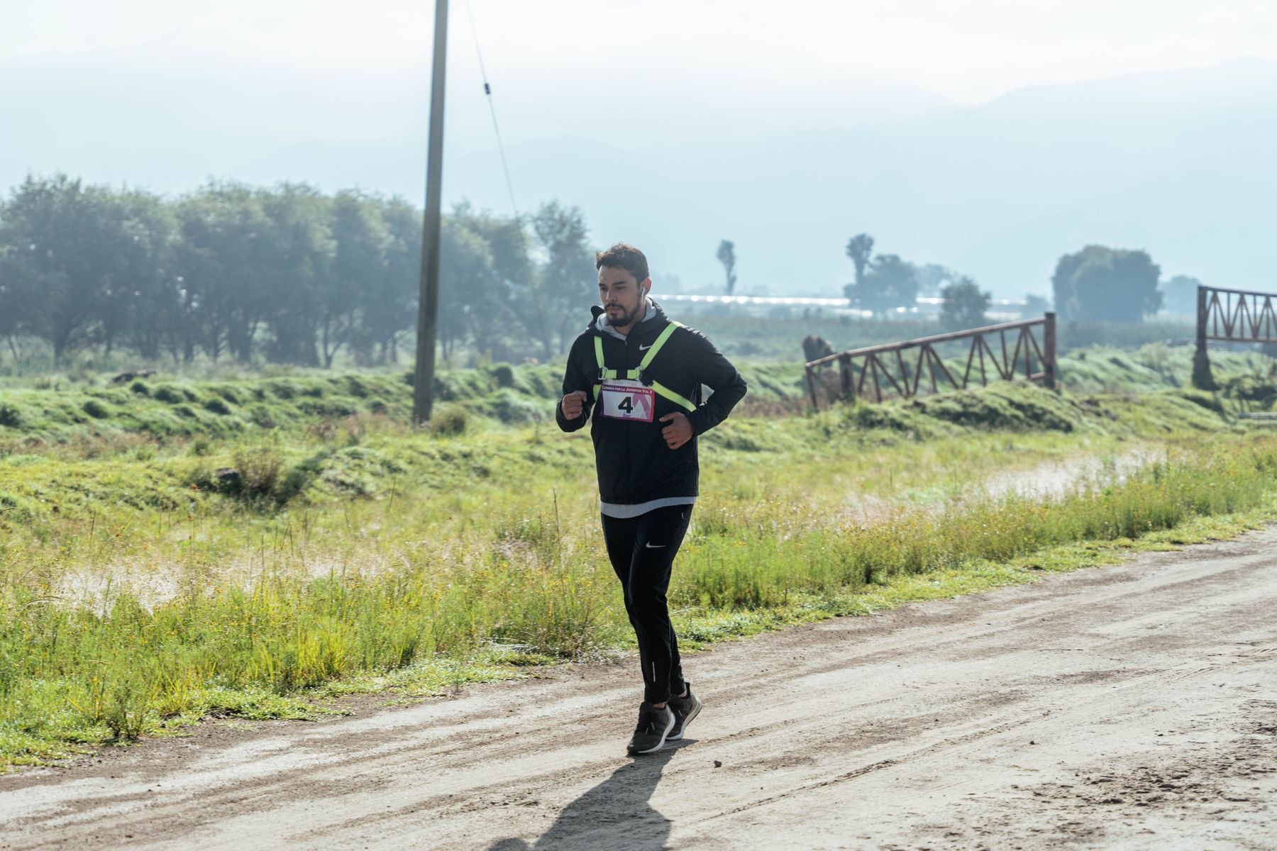 Man in black running clothes jogging along a rural trail