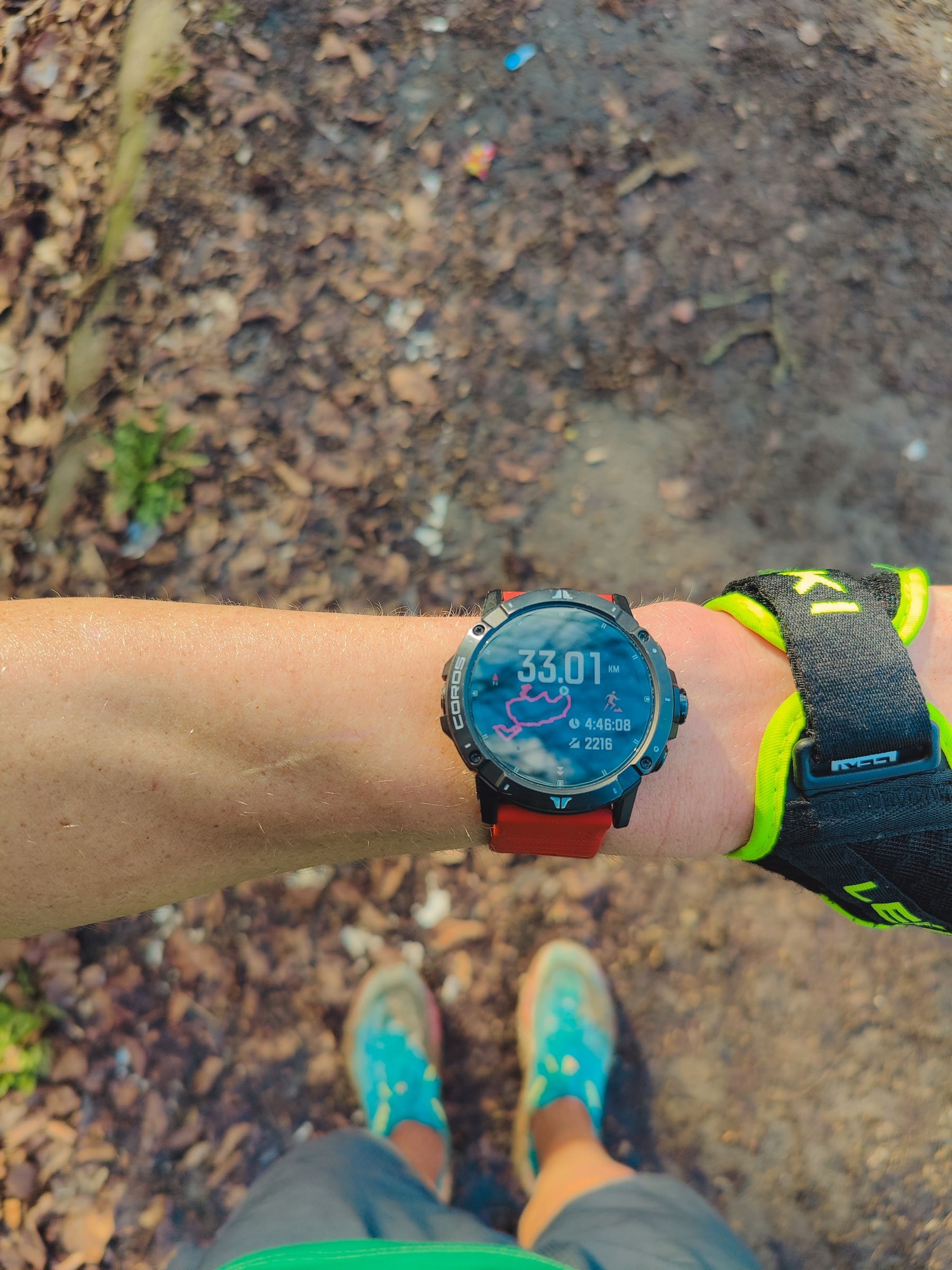 Runner looking at a smartwatch showing time and distance after a trail run