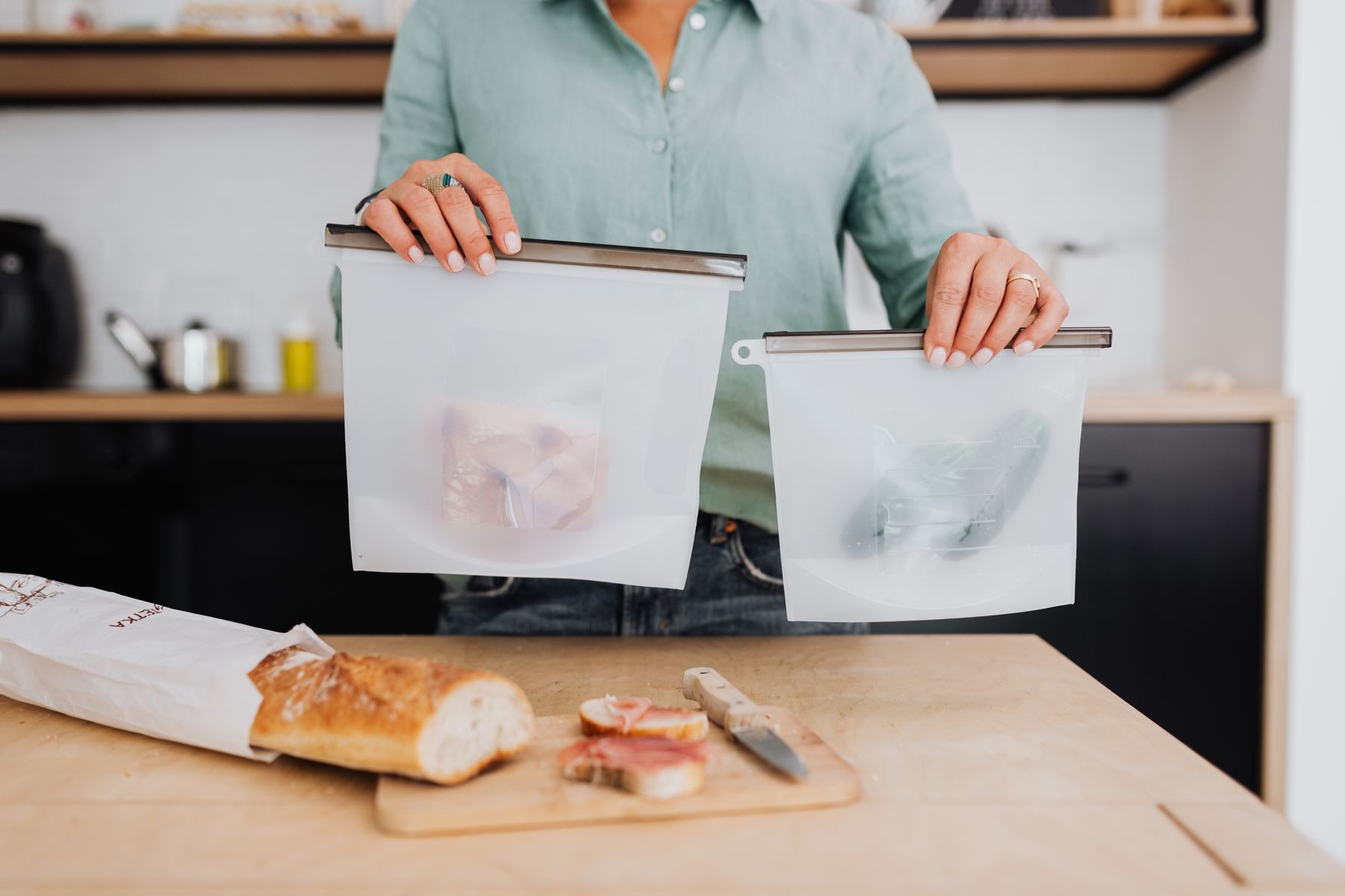 Woman holding two reusable silicone food bags over a kitchen counter