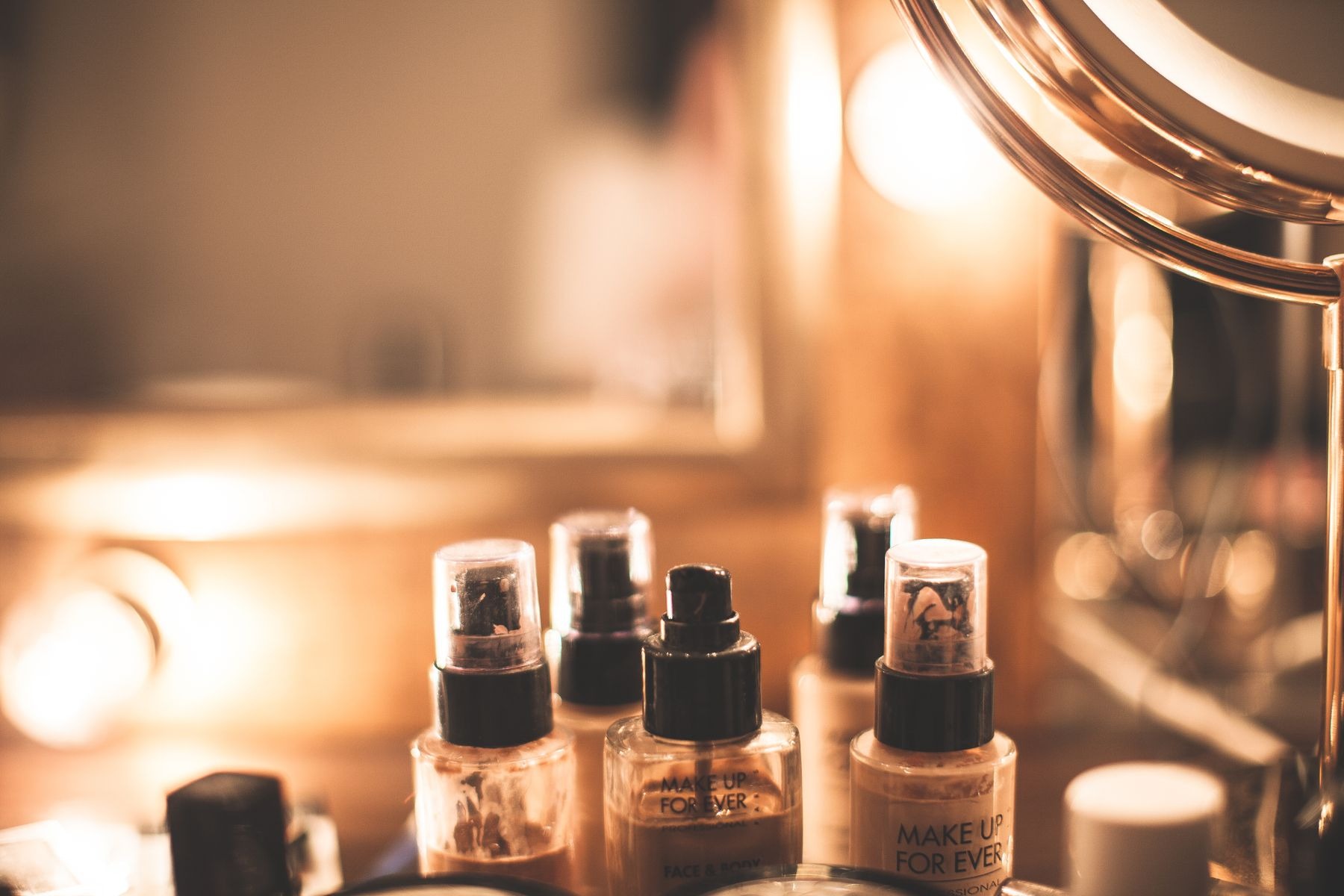 Glass bottles of liquid foundation and makeup products on a vanity table