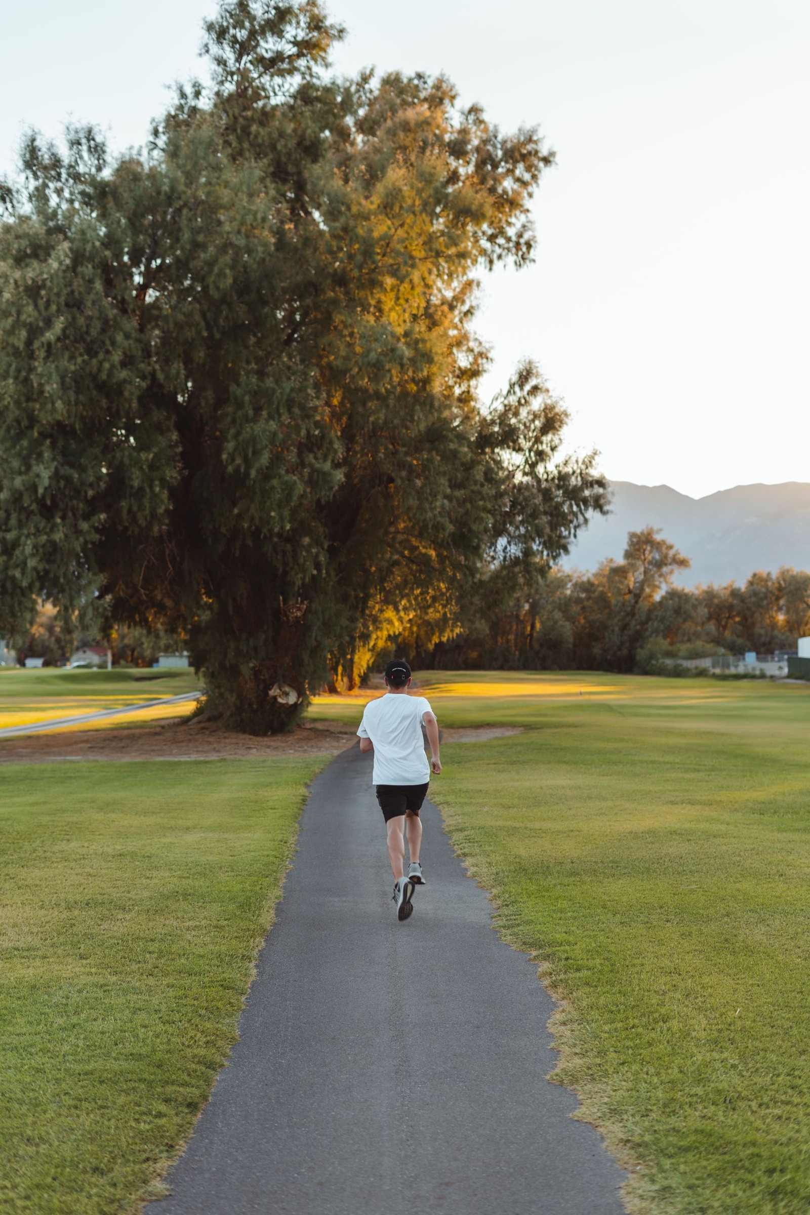 Rear view of a woman jogging along an empty paved park path