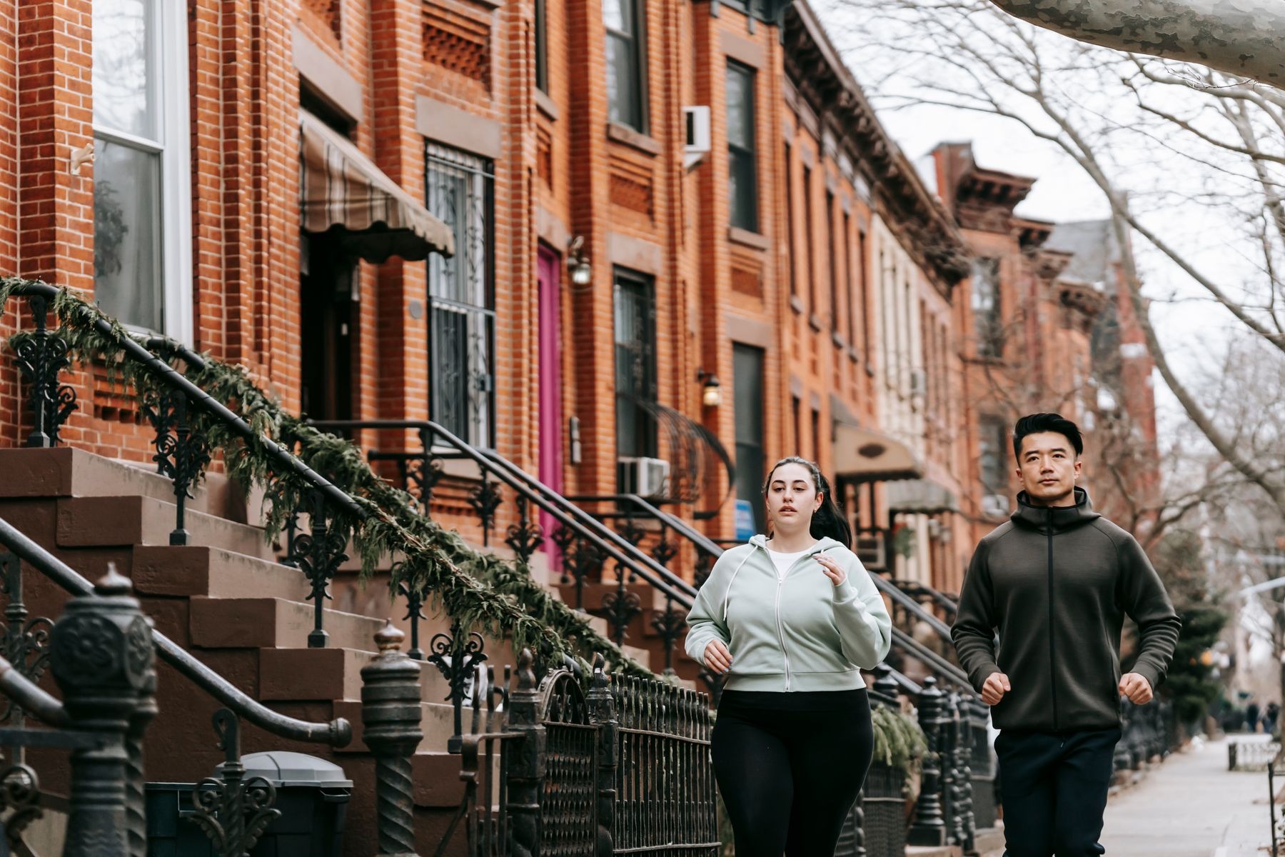 Woman and man jogging together on a residential street in autumn