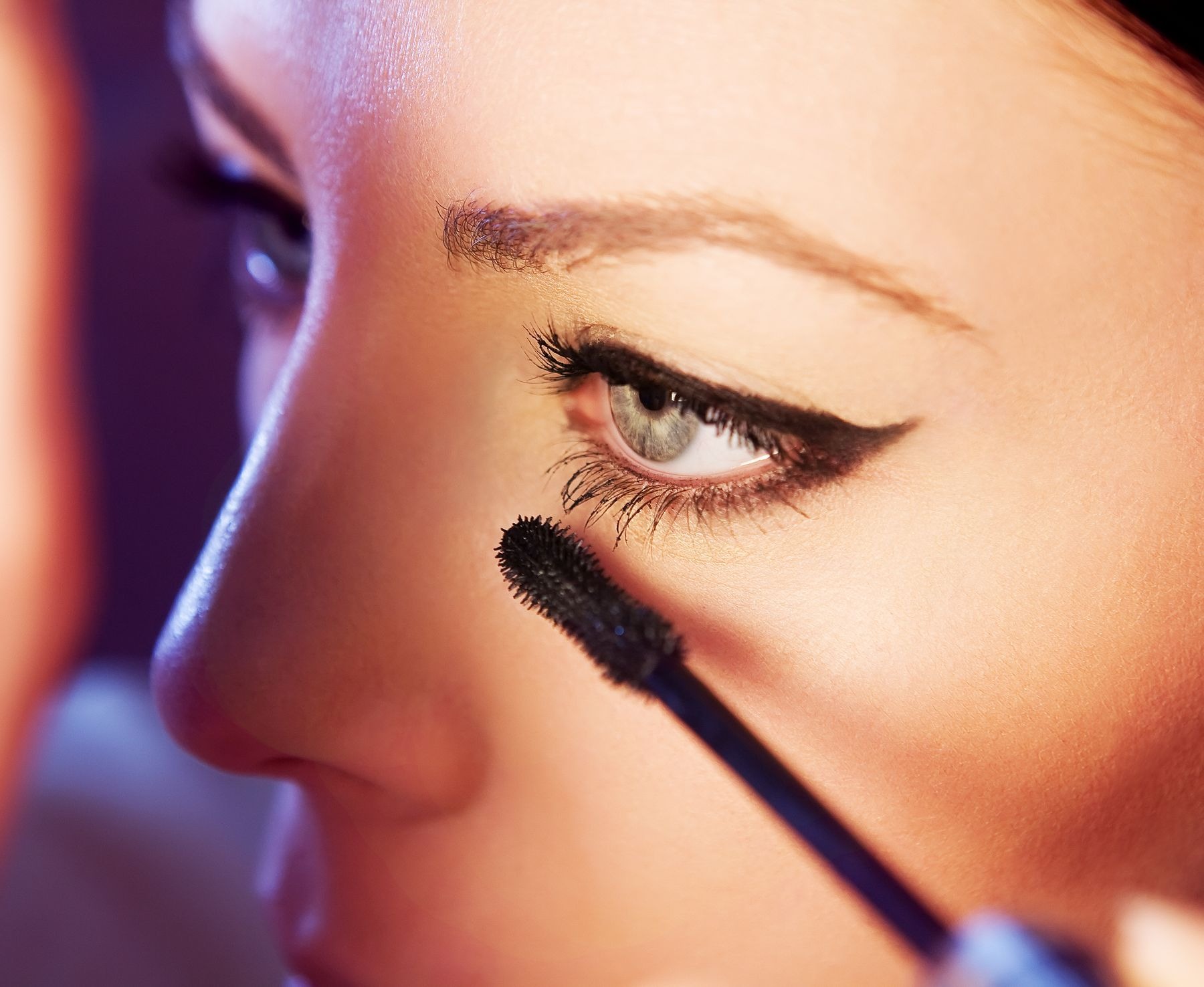 Detailed view of mascara being brushed through a woman's eyelashes