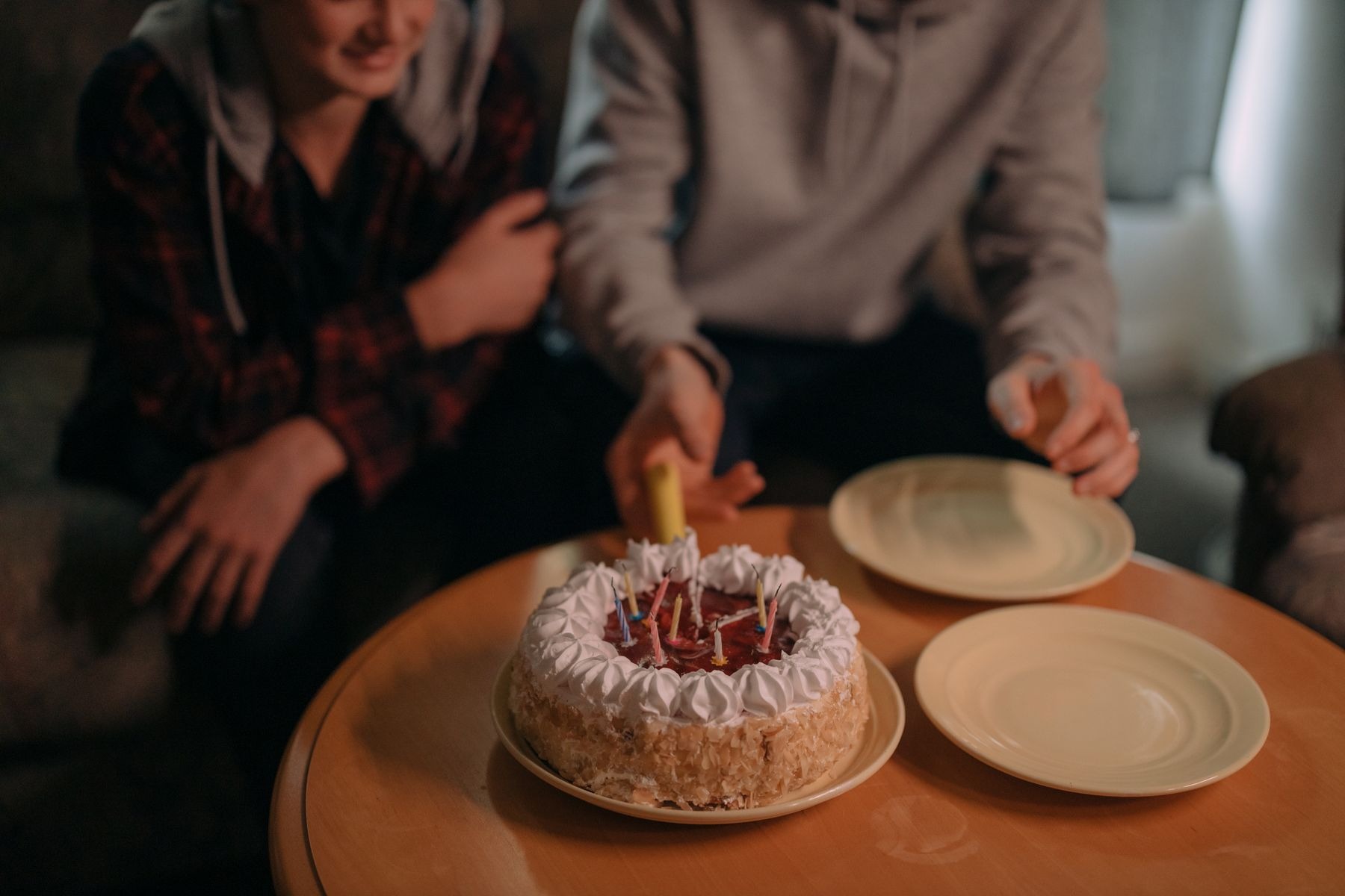 Friends celebrating with a birthday cake and plates on a table