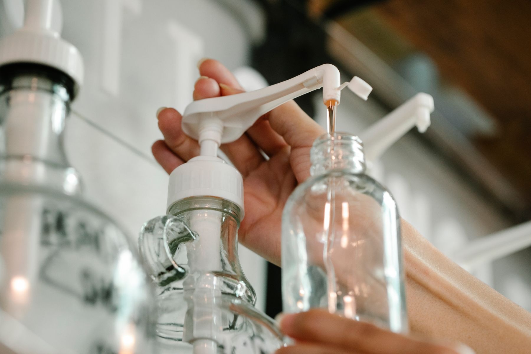Person dispensing soap into a plastic bottle for refilling