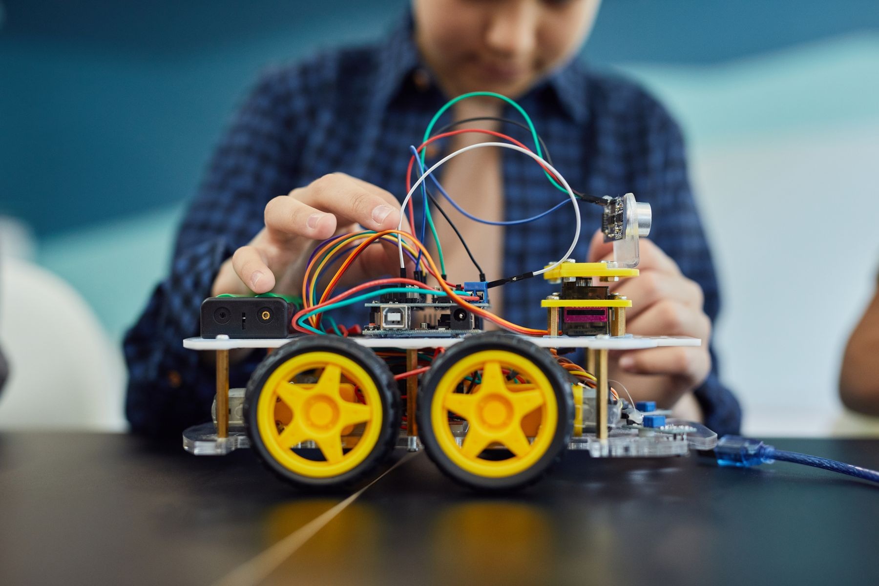 Hands working on wiring in a small toy vehicle or robot project