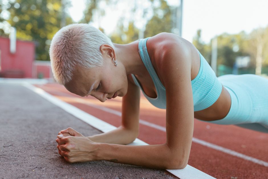 Woman planking on an outdoor track, showcasing fitness and determination.