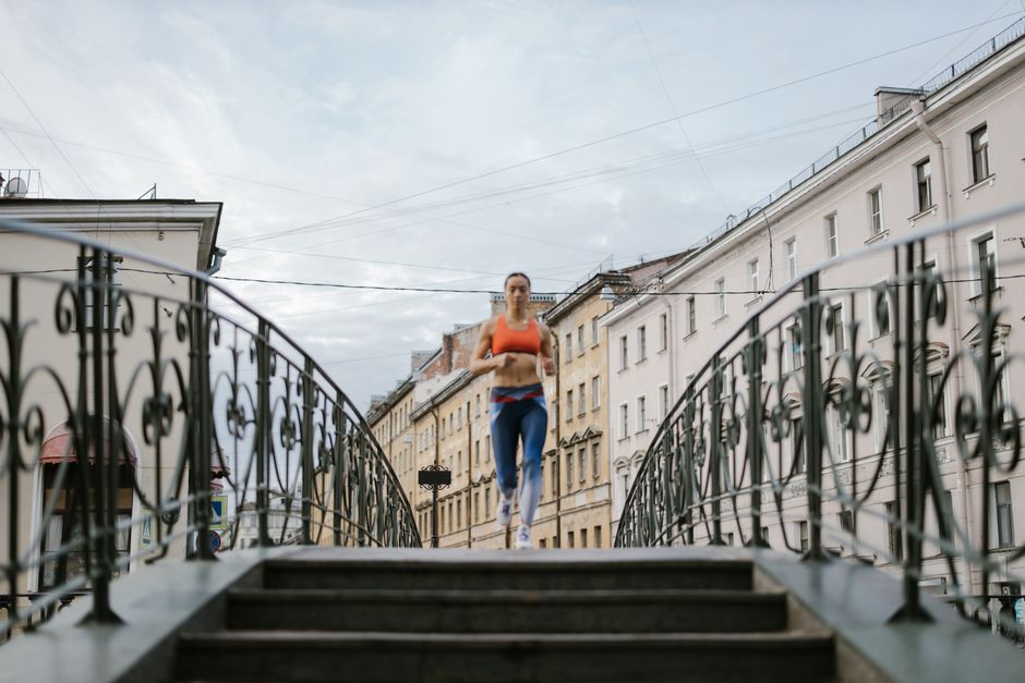 Woman running on a decorative city bridge, showcasing fitness and determination.